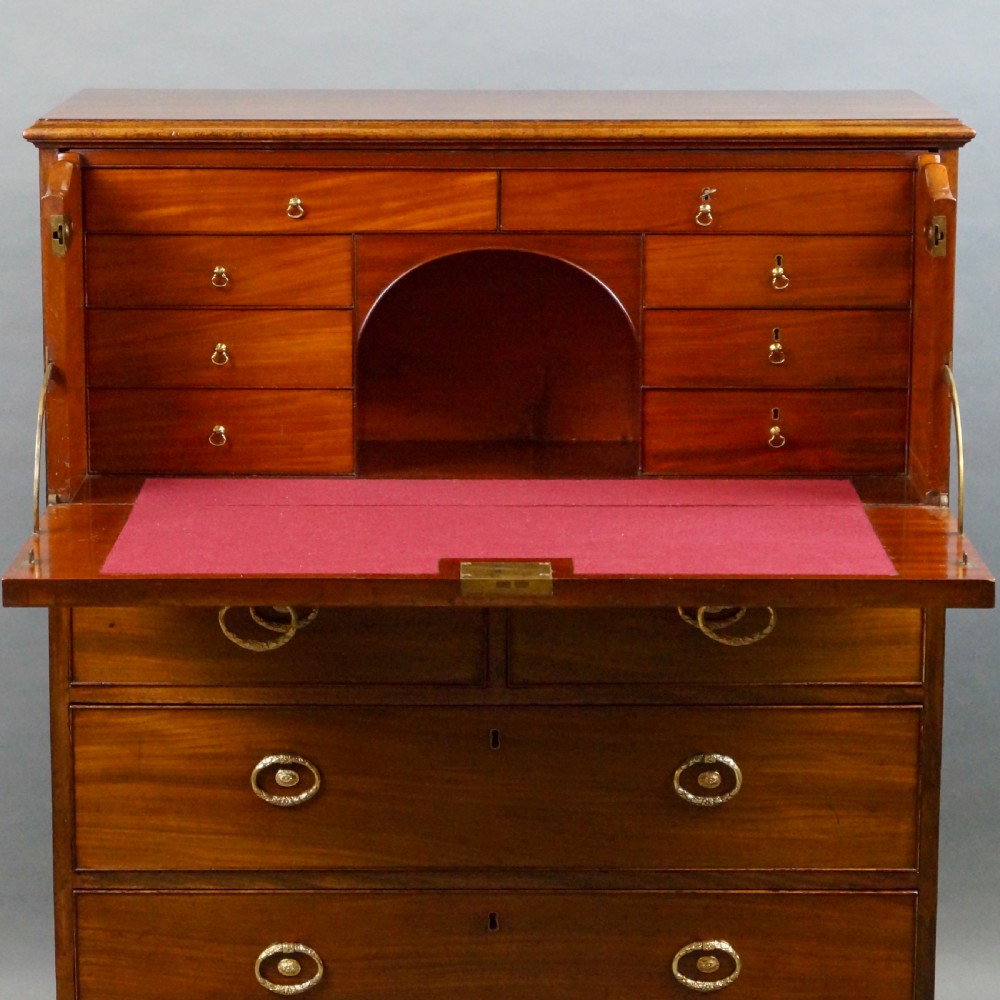 An antique mahogany secretaire chest of drawers featuring brass oval backplate handles, cockbeaded drawer edges, and bracket feet. View VIII
