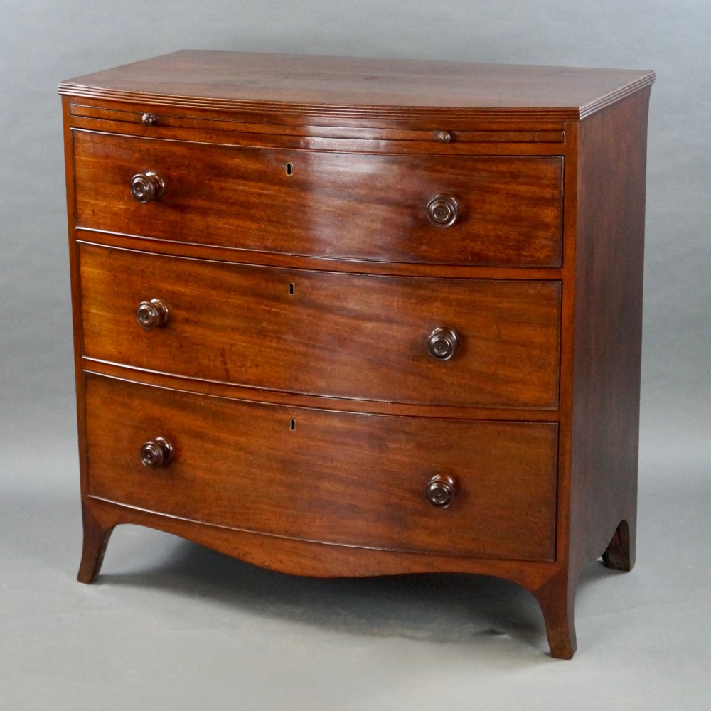 A George III bow-fronted mahogany chest featuring three graduated long drawers with turned wooden knobs and bracket feet. View III