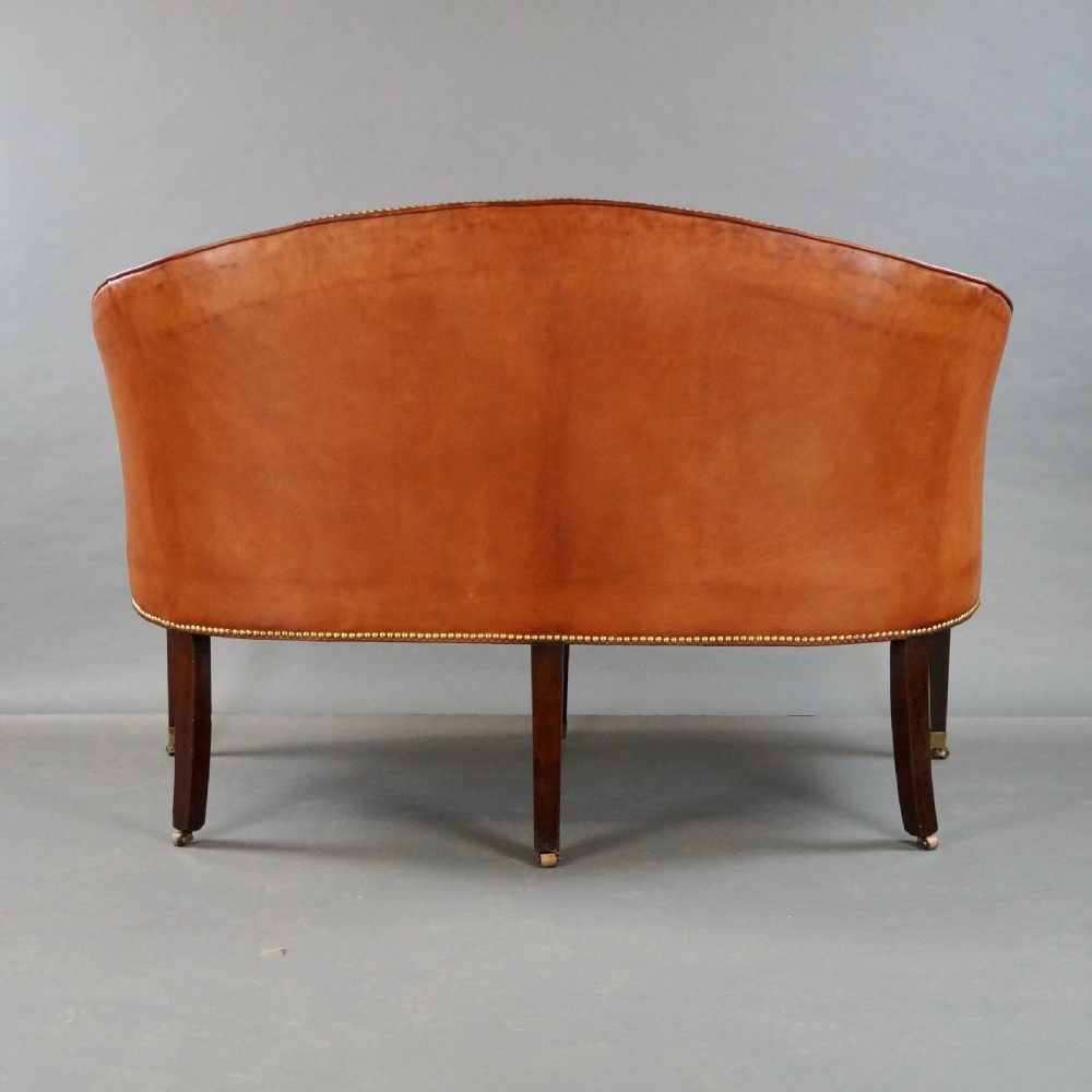 An 18th-century Hepplewhite period sofa upholstered in tan leather with brass stud trimming and tapered mahogany legs on brass castors. View VIII
