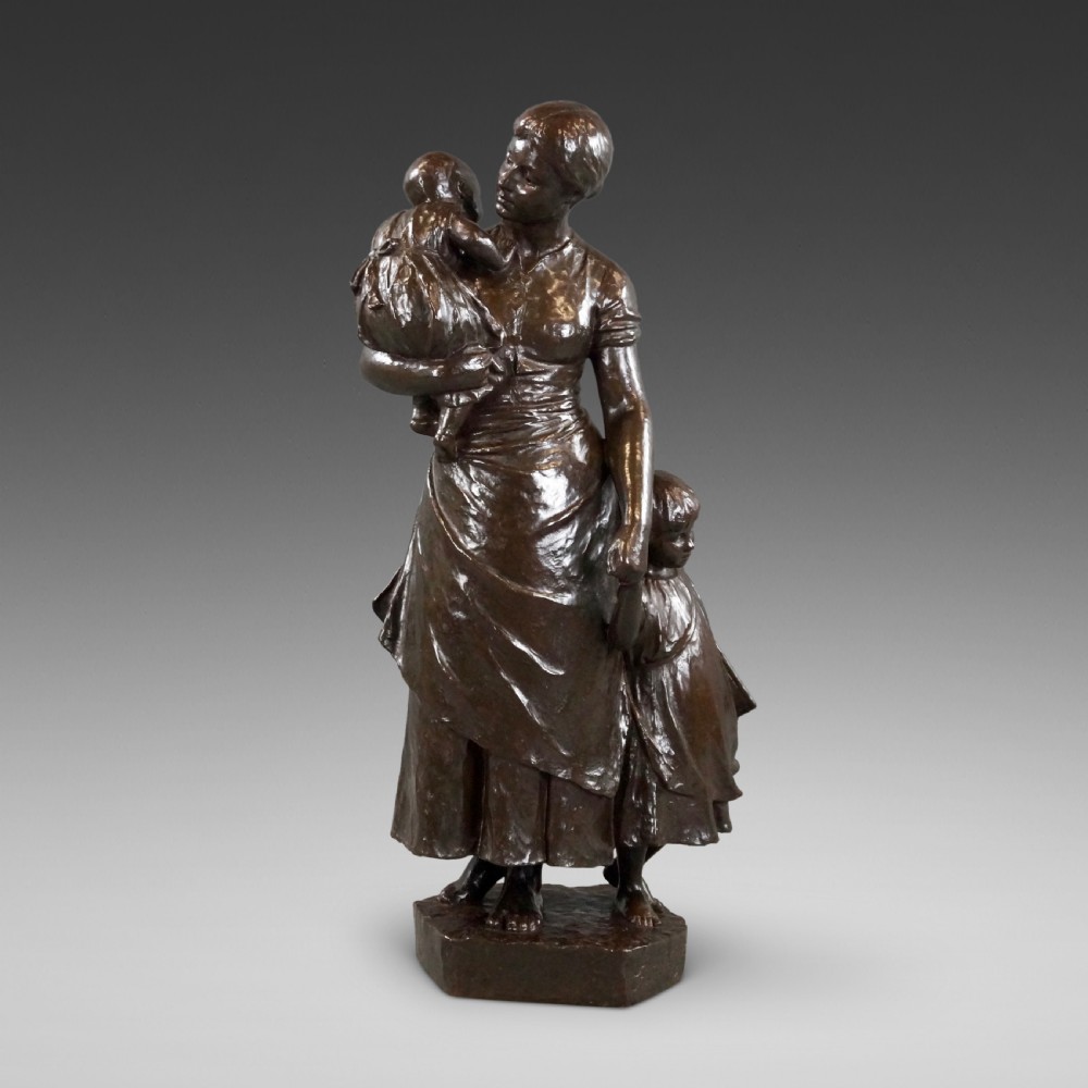 A dark brown patinated bronze figural sculpture depicting a standing mother holding an infant with a young child standing at her side.