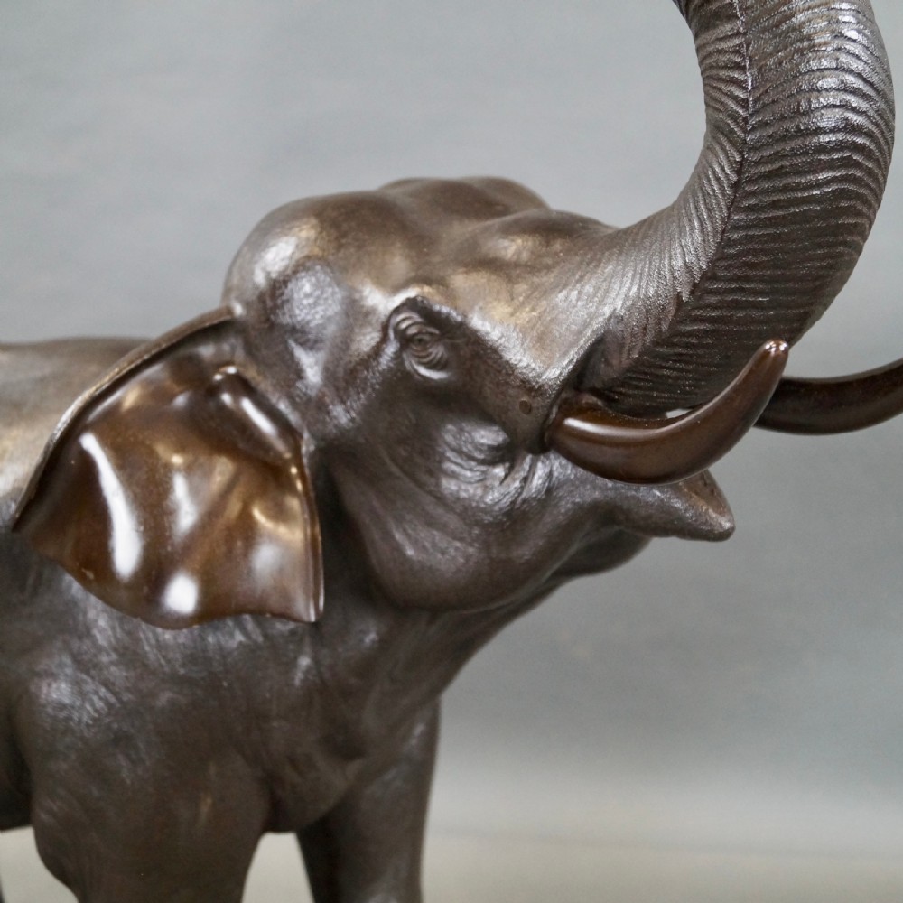 A cast bronze sculpture of an elephant standing with its trunk raised high, created in the Japanese Meiji style. View V