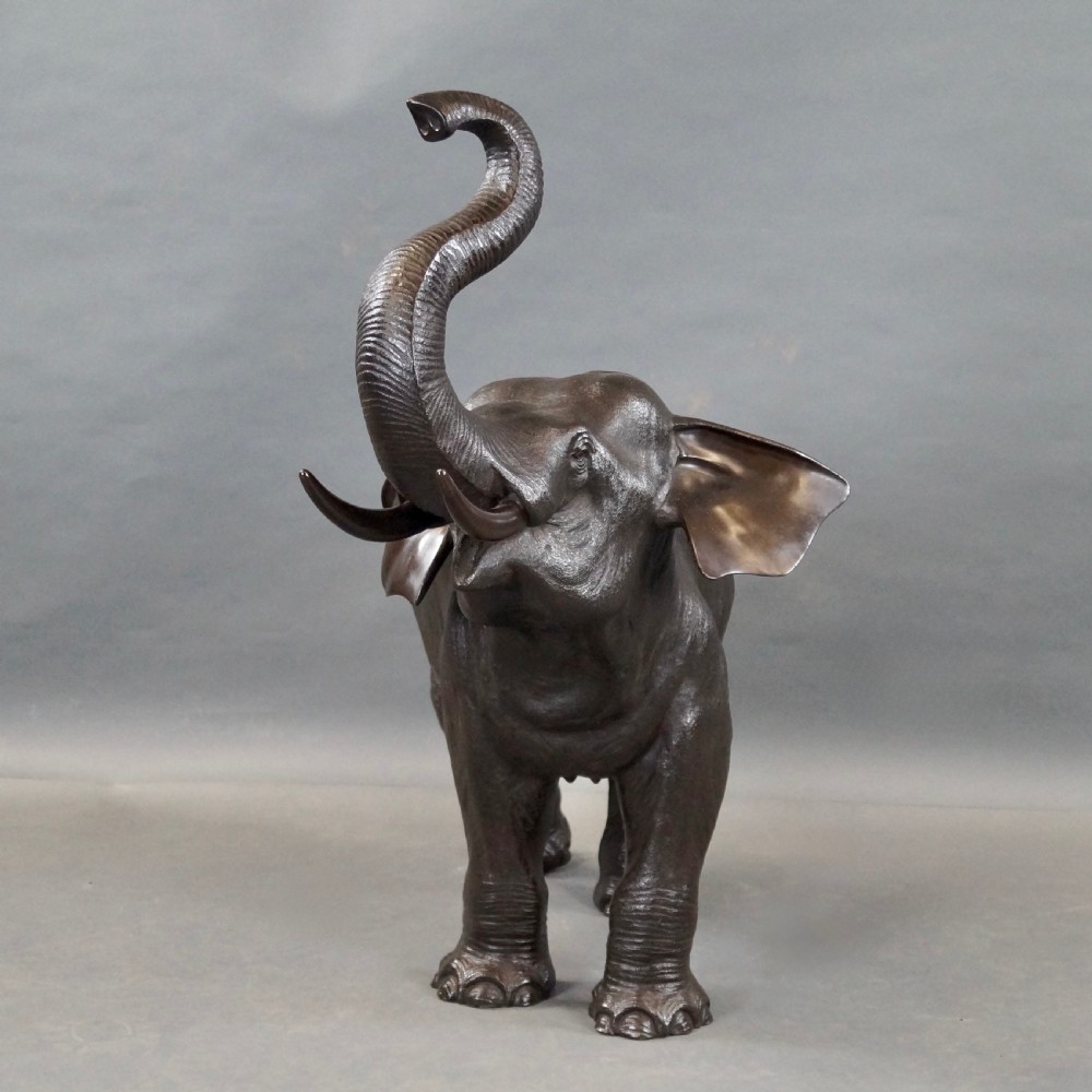 A cast bronze sculpture of an elephant standing with its trunk raised high, created in the Japanese Meiji style. View VI