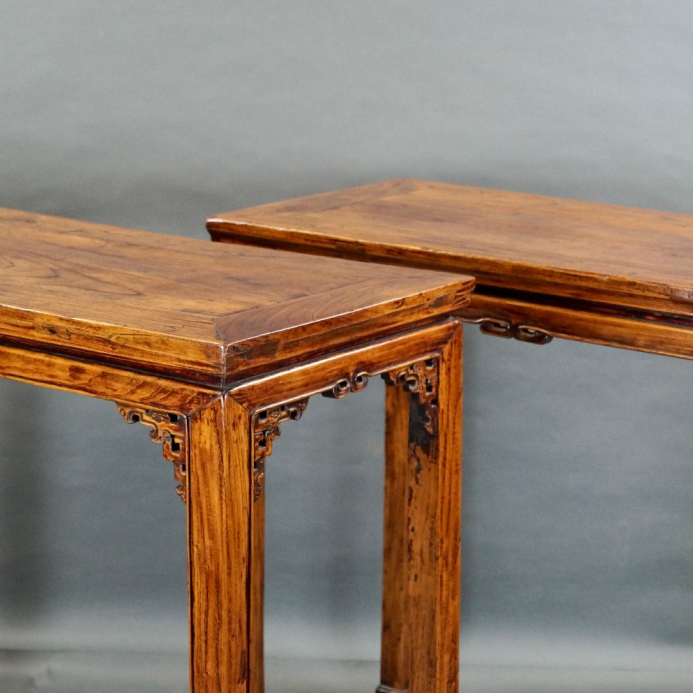 A pair of 19th-century Chinese elm side tables featuring rectangular floating panel tops, carved corner spandrels, and tall straight legs. View V