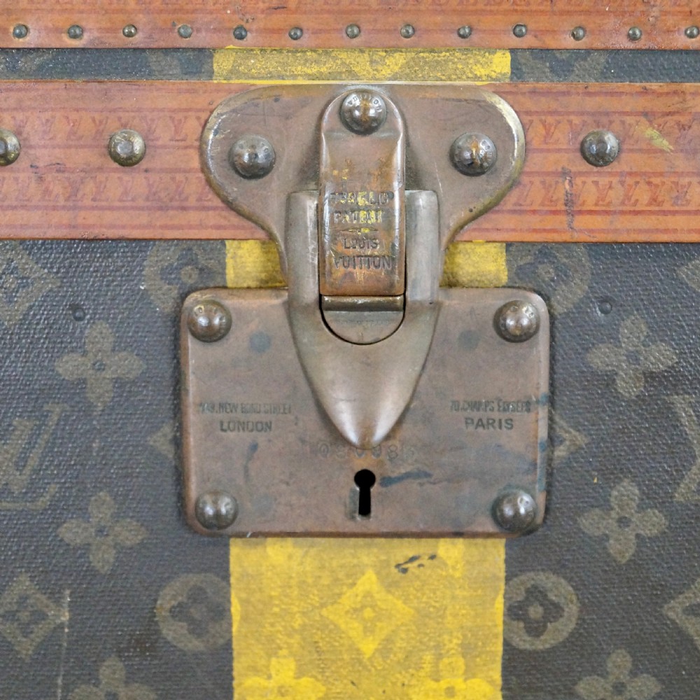 An upright 1930s Louis Vuitton monogram canvas wardrobe trunk featuring leather trim, brass hardware, and custom yellow painted stripes. View VI