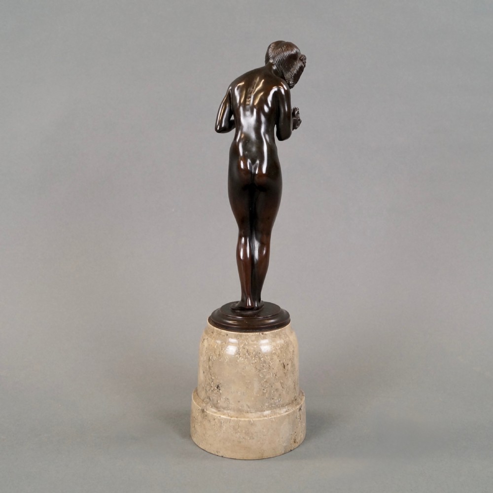 An Art Deco dark bronze sculpture depicting a standing female nude holding a small frog, mounted on a cylindrical veined marble pedestal base. View III