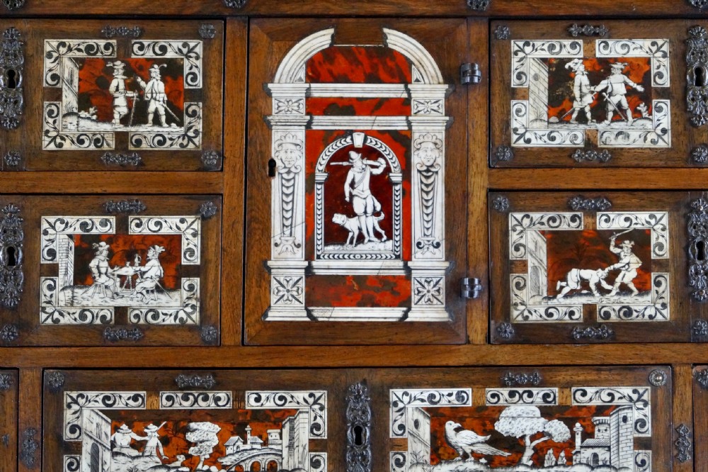 A 19th-century Portuguese cabinet on stand featuring inlaid bone figurative scenes, multiple drawer fronts surrounding a central arch, and a stand supported by dark spiral-turned legs. View II
