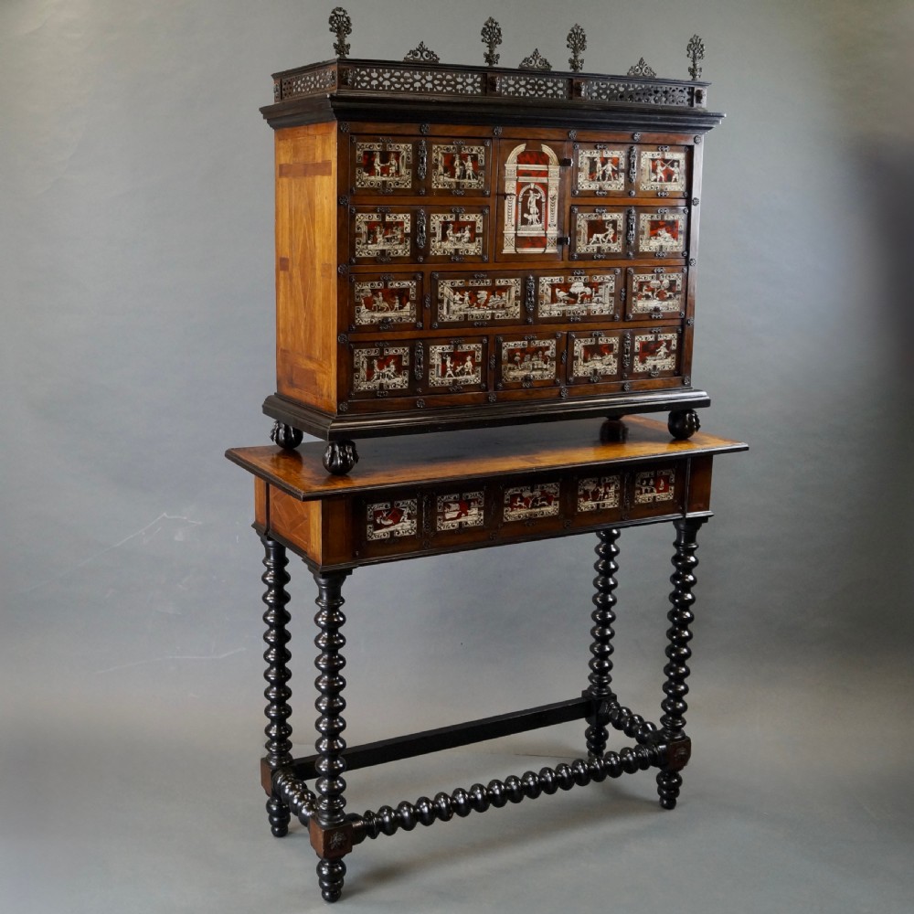 A 19th-century Portuguese cabinet on stand featuring inlaid bone figurative scenes, multiple drawer fronts surrounding a central arch, and a stand supported by dark spiral-turned legs. View V