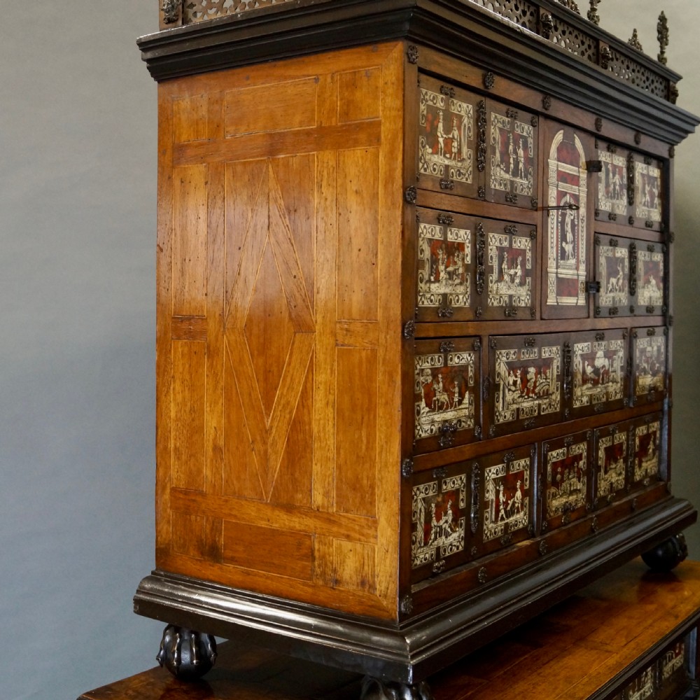 A 19th-century Portuguese cabinet on stand featuring inlaid bone figurative scenes, multiple drawer fronts surrounding a central arch, and a stand supported by dark spiral-turned legs. View VI