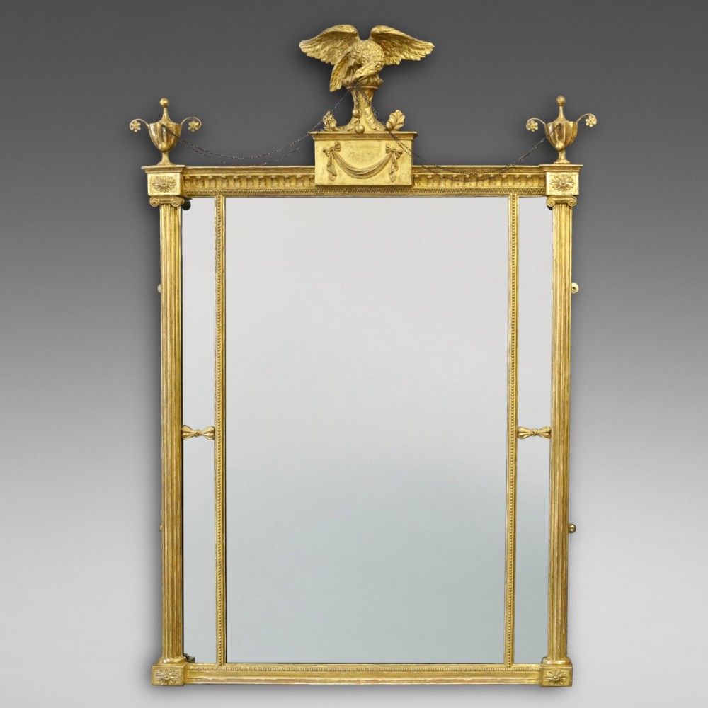 A rectangular 18th-century Neoclassical giltwood wall mirror featuring fluted side columns, corner urn finials, and a central eagle cresting.