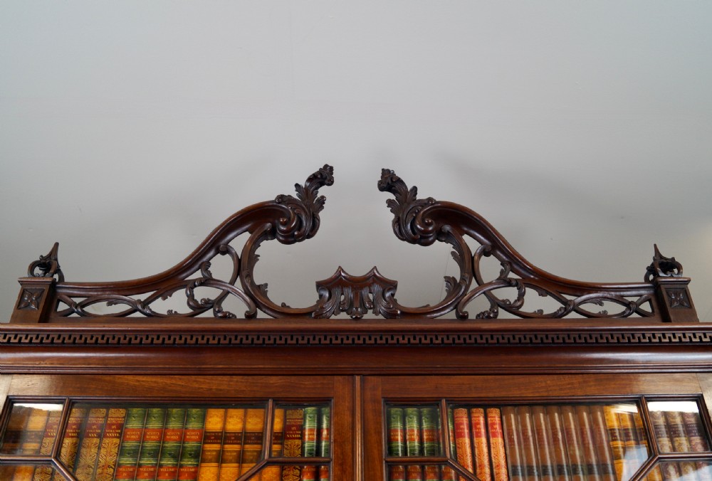 A George III mahogany bureau bookcase featuring a carved fretwork pediment, two astragal glazed upper doors, a sloping fall-front desk, and four graduated drawers with brass handles. View III