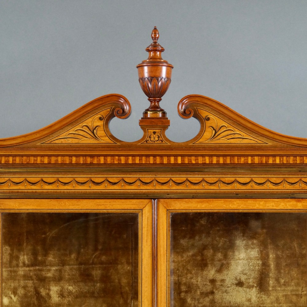 An antique satinwood display cabinet featuring marquetry inlays, glazed double-tier doors, turned support columns, and an ornamental top finial. View II