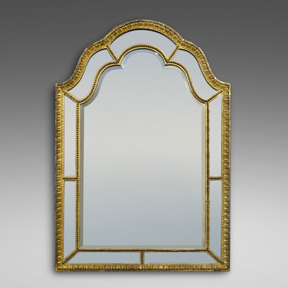 A nineteenth-century French giltwood wall mirror featuring an arched top crest, beaded trim, and marginal mirror plate borders.