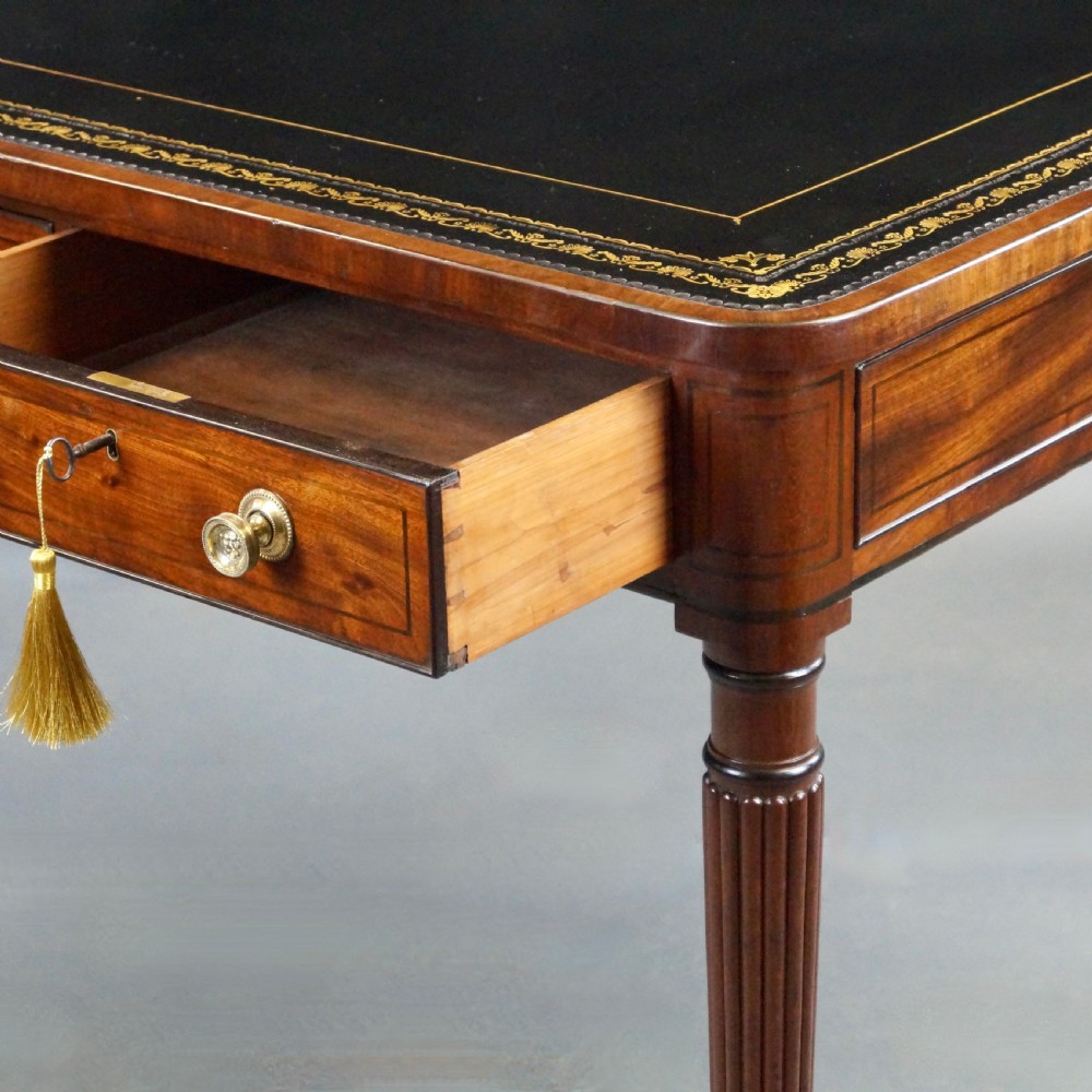 A George III mahogany partners writing table featuring a gold-tooled leather top, three drawers with brass knob handles, and fluted legs on brass castors. View VI