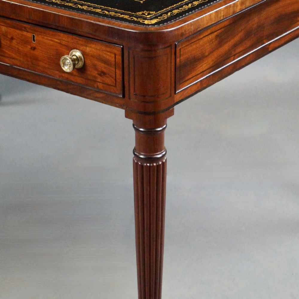 A George III mahogany partners writing table featuring a gold-tooled leather top, three drawers with brass knob handles, and fluted legs on brass castors. View VIII