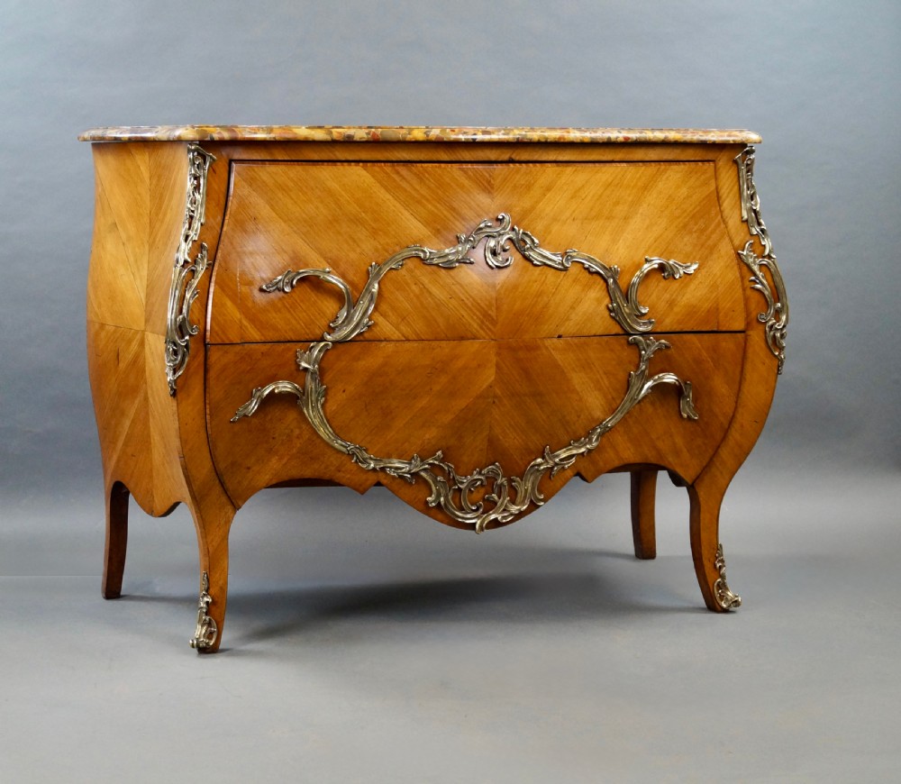 A nineteenth-century French bombe commode featuring chevron parquetry veneer, ornate scrollwork metal mounts, and a shaped marble top. View II