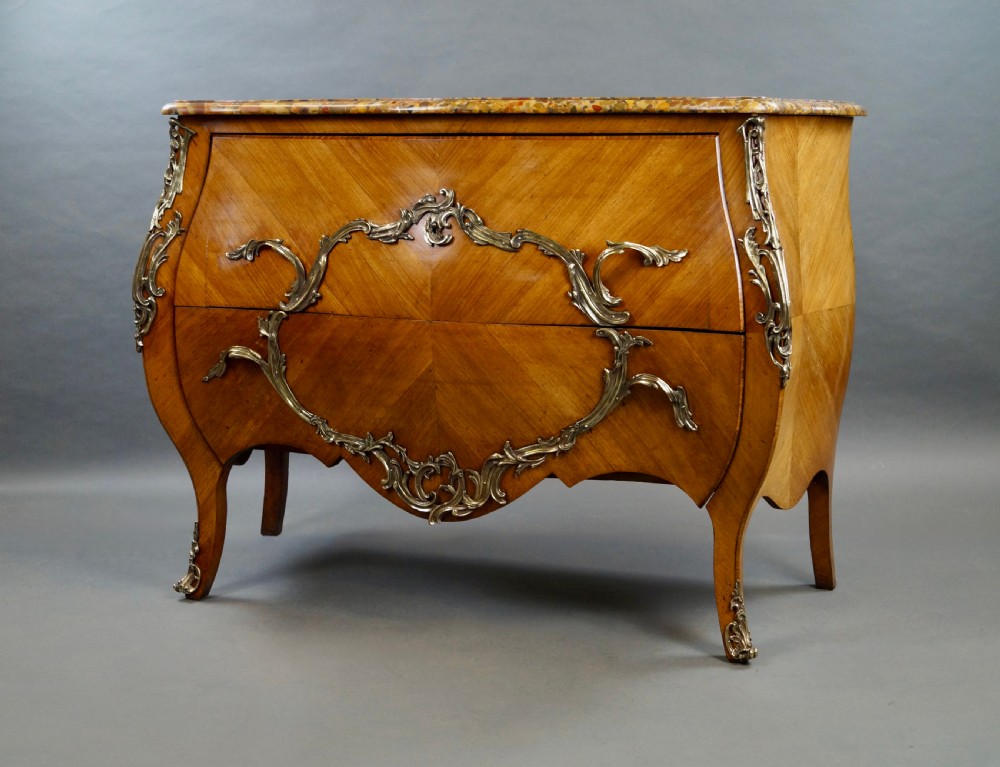 A nineteenth-century French bombe commode featuring chevron parquetry veneer, ornate scrollwork metal mounts, and a shaped marble top. View VI
