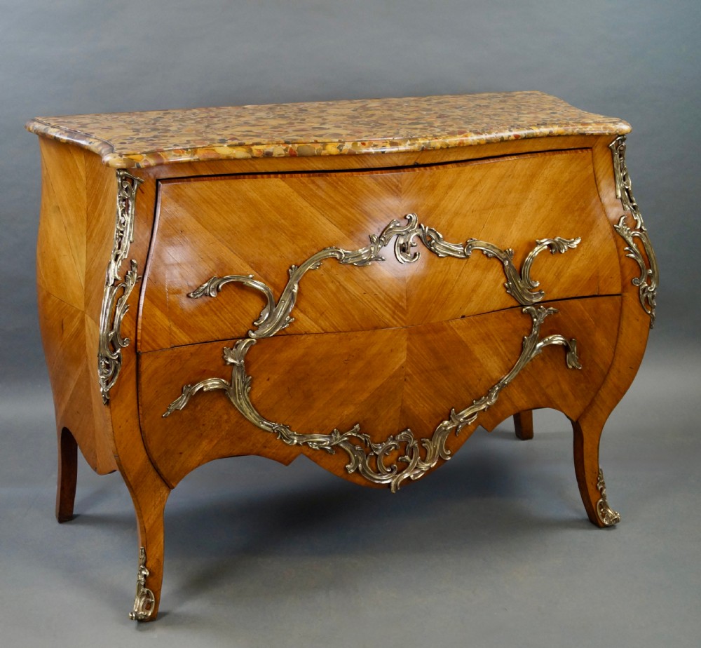 A nineteenth-century French bombe commode featuring chevron parquetry veneer, ornate scrollwork metal mounts, and a shaped marble top. View VII