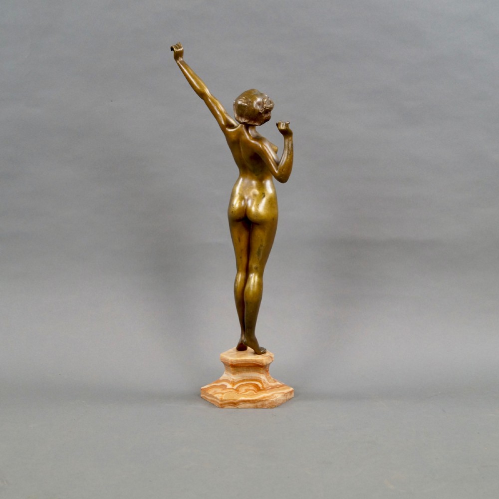 A stylised Art Deco gilt bronze statuette depicting a standing female nude with raised arms, mounted on a stepped onyx plinth base. View III