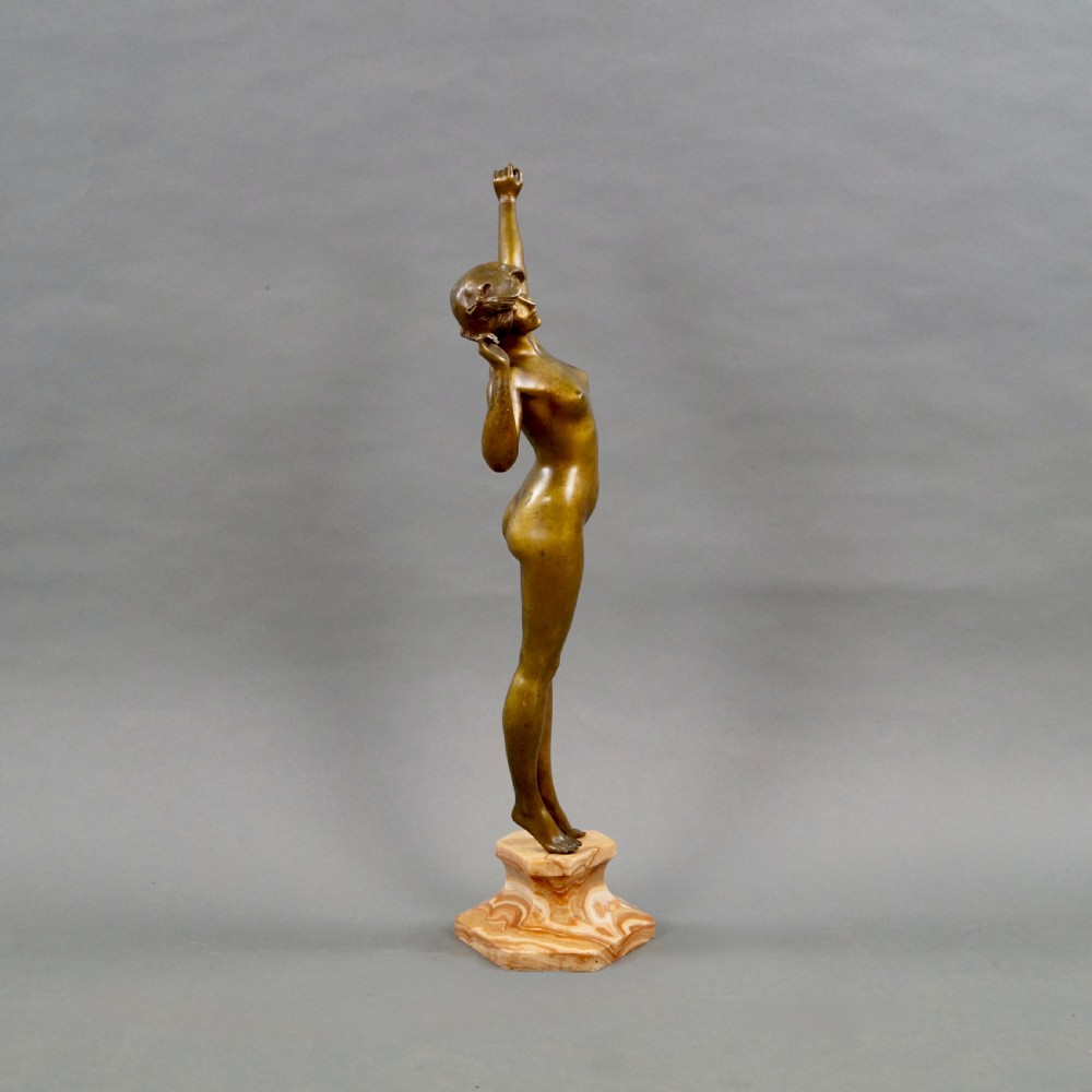 A stylised Art Deco gilt bronze statuette depicting a standing female nude with raised arms, mounted on a stepped onyx plinth base. View IV