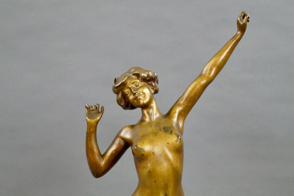 A stylised Art Deco gilt bronze statuette depicting a standing female nude with raised arms, mounted on a stepped onyx plinth base. View V