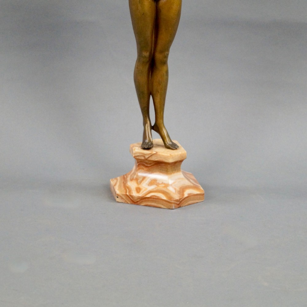 A stylised Art Deco gilt bronze statuette depicting a standing female nude with raised arms, mounted on a stepped onyx plinth base. View VI