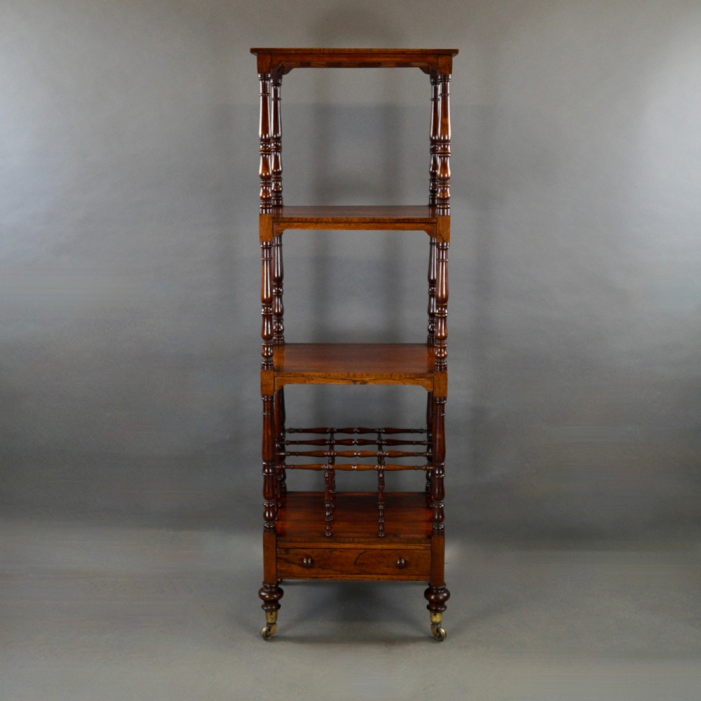 A tall four-tier antique rosewood whatnot featuring slender turned upright supports, a spindle divider shelf, a lower drawer, and brass castors. View III