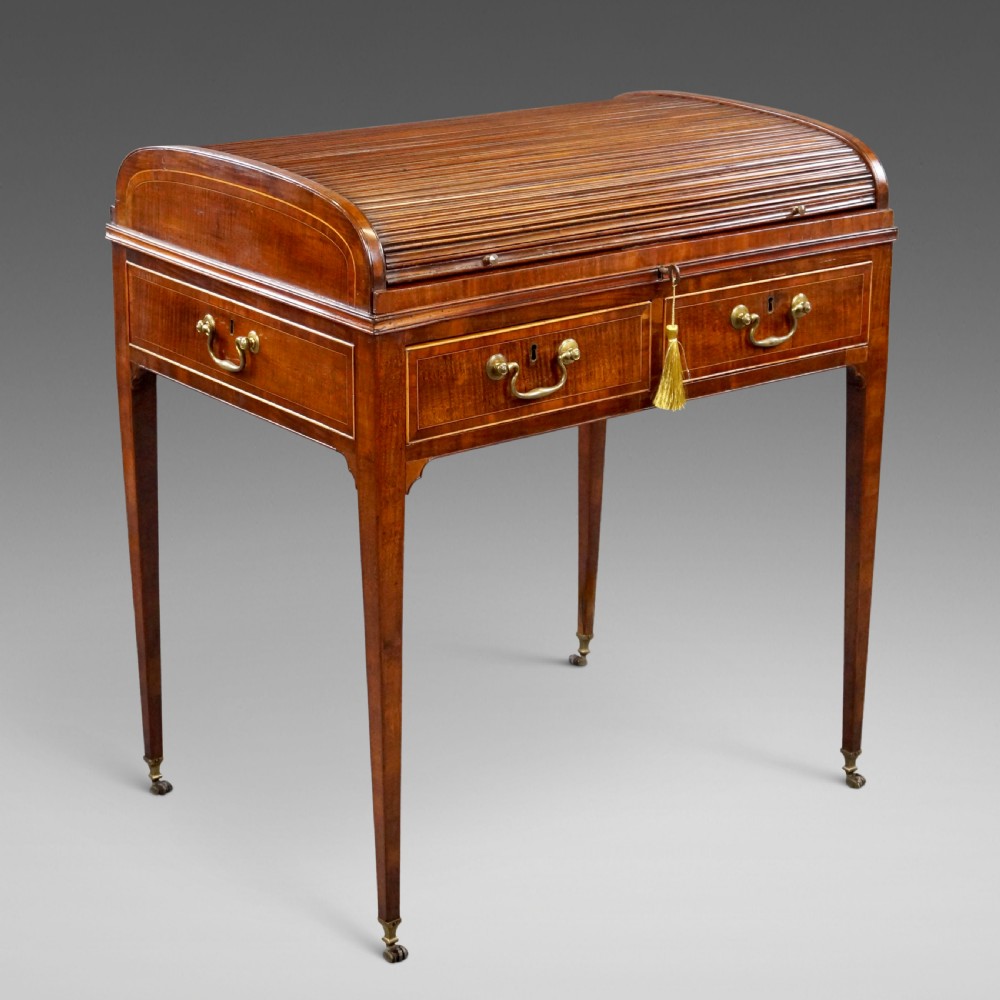 A George III mahogany tambour desk with a curved slatted roll top, drawer brass handles, fine inlay stringing, and square tapered legs fitted with brass castors.