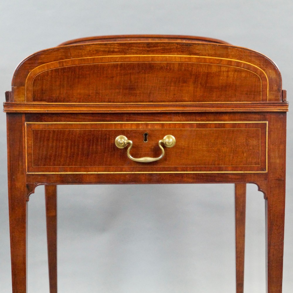 A George III mahogany tambour desk with a curved slatted roll top, drawer brass handles, fine inlay stringing, and square tapered legs fitted with brass castors. View VI