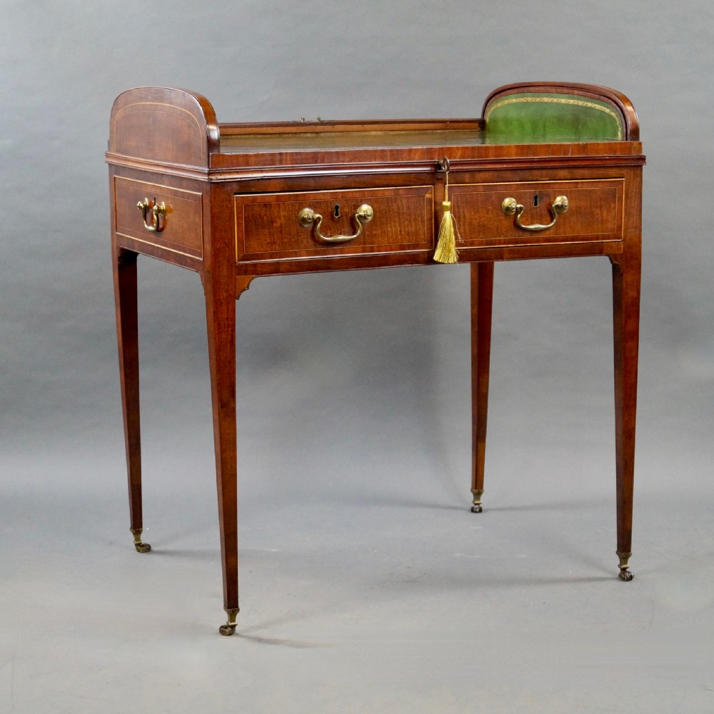 A George III mahogany tambour desk with a curved slatted roll top, drawer brass handles, fine inlay stringing, and square tapered legs fitted with brass castors. View VII