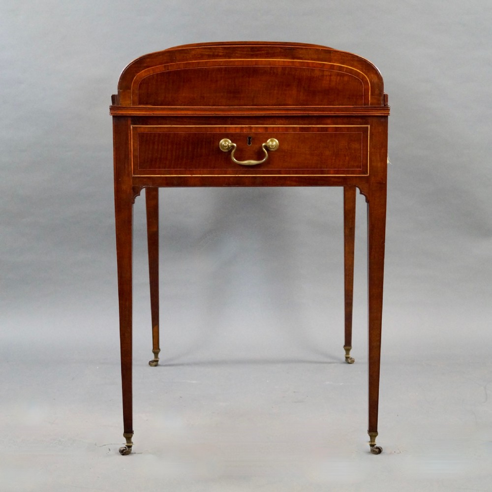 A George III mahogany tambour desk with a curved slatted roll top, drawer brass handles, fine inlay stringing, and square tapered legs fitted with brass castors. View VIII