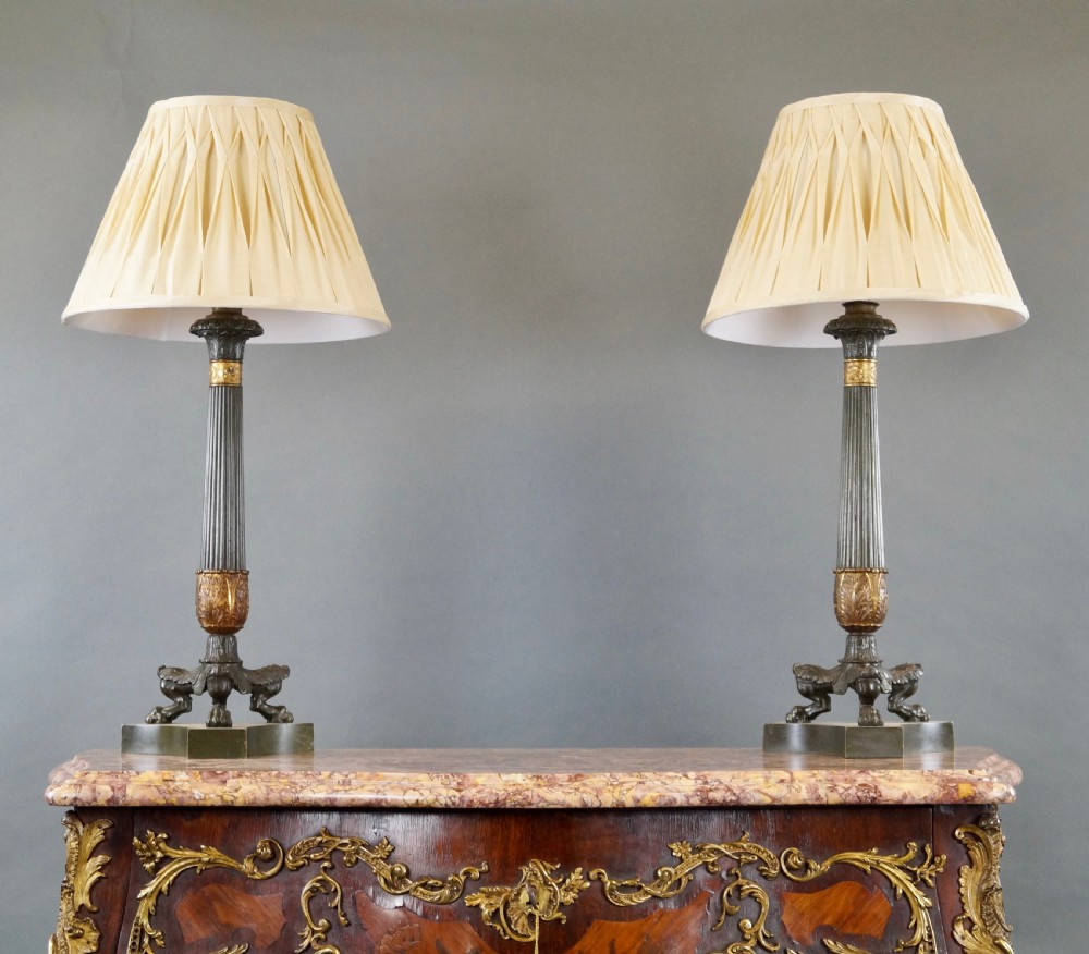 A pair of Neoclassical style dark patinated bronze table lamps featuring fluted columns, gilt bronze mounts, paw feet, and cream pleated shades. View VI