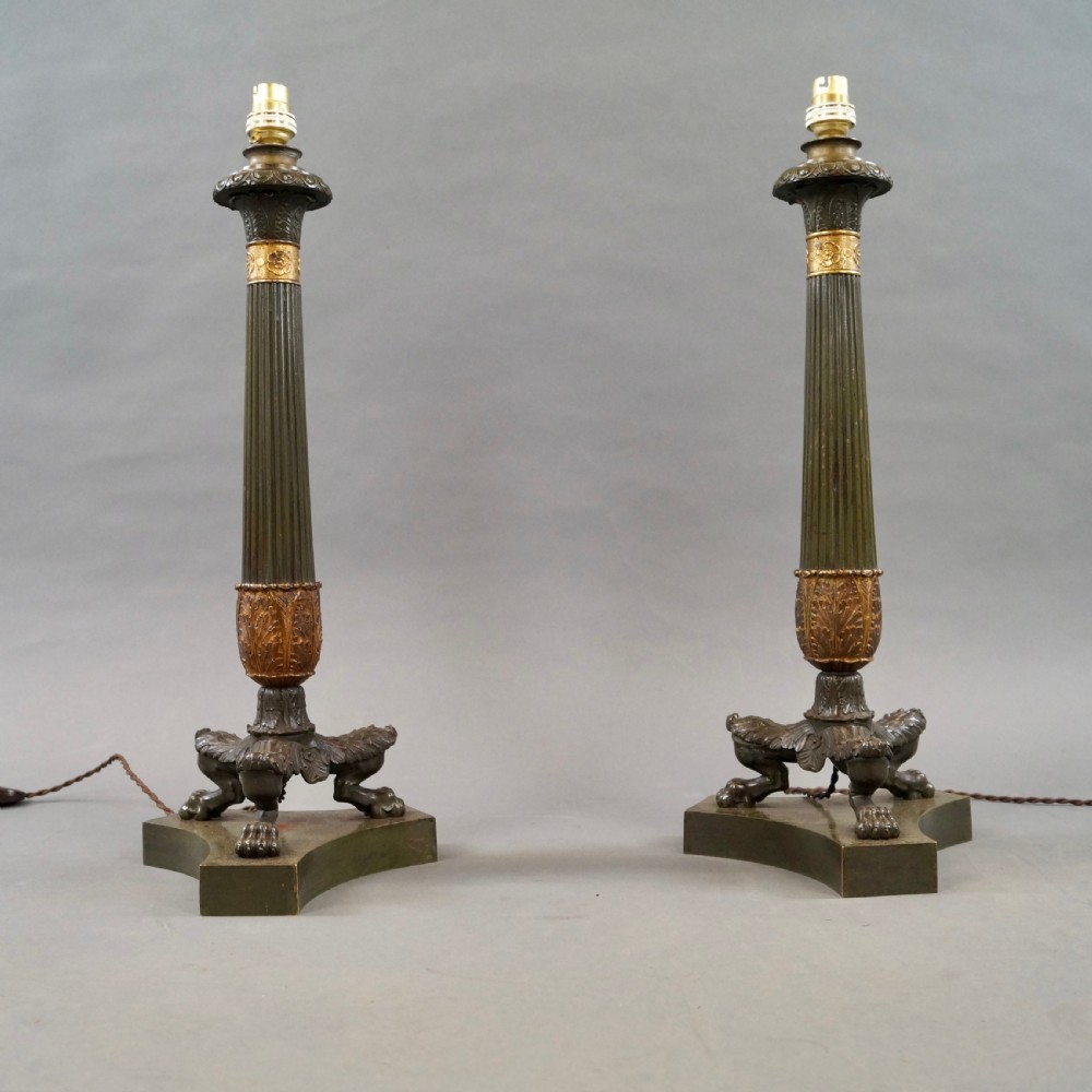 A pair of Neoclassical style dark patinated bronze table lamps featuring fluted columns, gilt bronze mounts, paw feet, and cream pleated shades. View VII