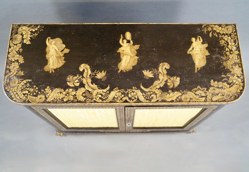 A Regency period black pen-work side cabinet featuring gold vine motifs, pleated yellow silk door panels, and gilded paw feet. View V