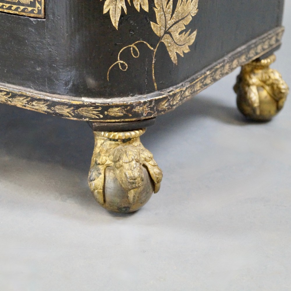 A Regency period black pen-work side cabinet featuring gold vine motifs, pleated yellow silk door panels, and gilded paw feet. View VIII
