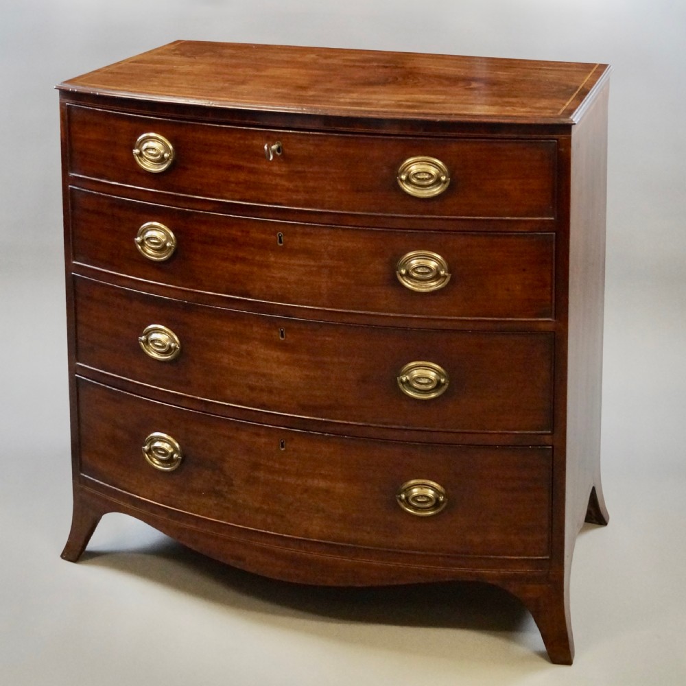 A George III mahogany bow-fronted chest featuring four graduated drawers with oval brass handles and splayed bracket feet. View II