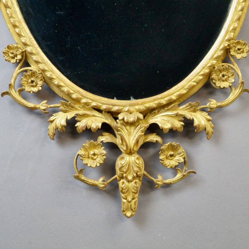 A pair of 18th-century oval giltwood wall mirrors featuring carved floral surrounds and fruit-filled urn finials. View III