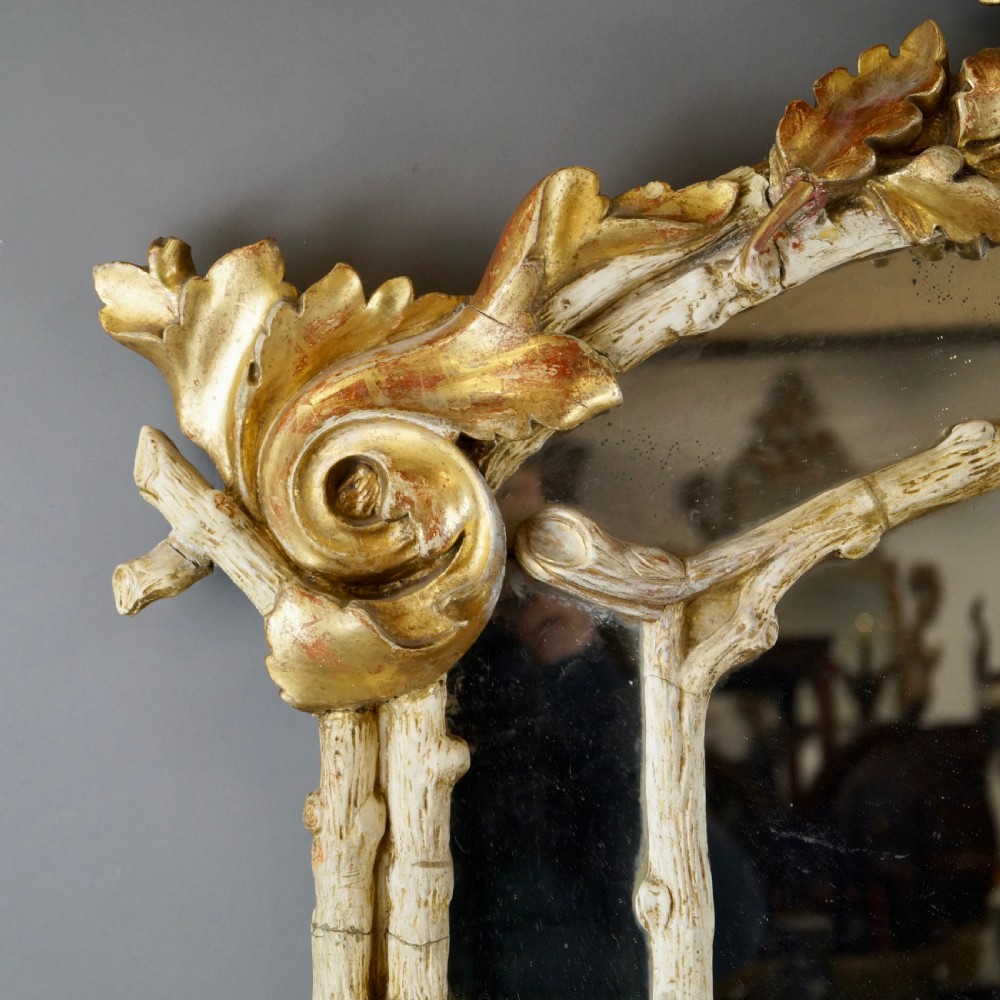A large 18th-century wall mirror featuring an ornate carved giltwood frame with foliage cresting and a central arched mirror plate. View III