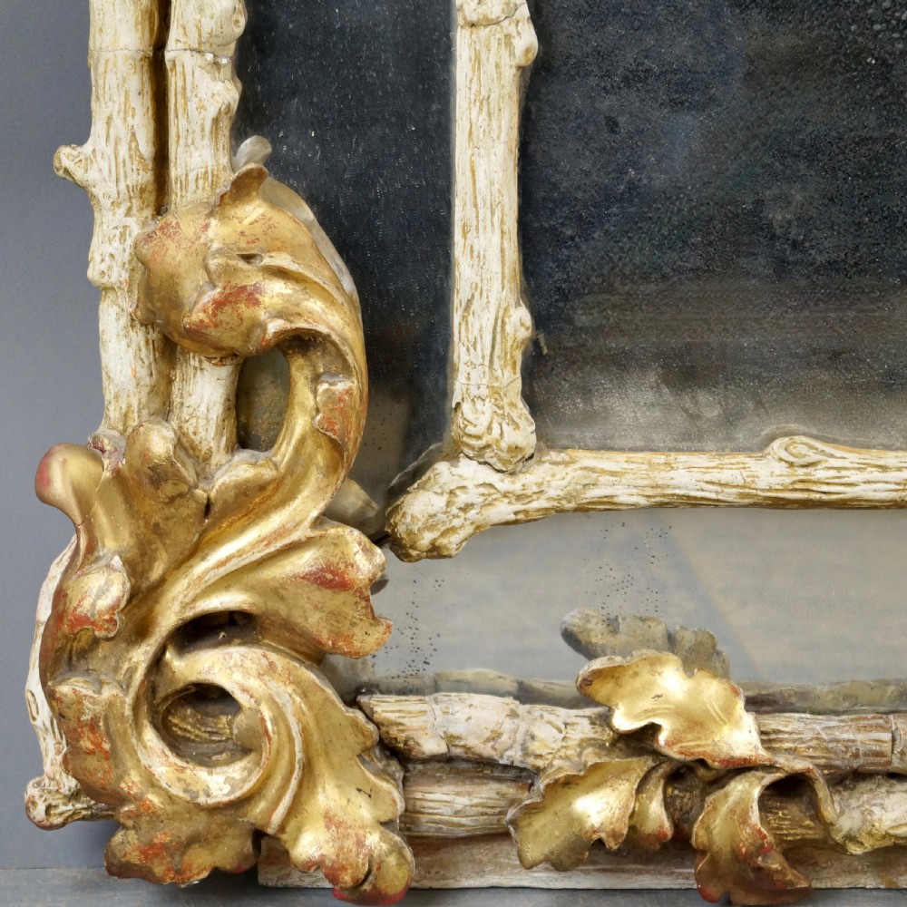A large 18th-century wall mirror featuring an ornate carved giltwood frame with foliage cresting and a central arched mirror plate. View VI