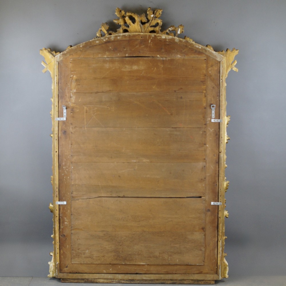 A large 18th-century wall mirror featuring an ornate carved giltwood frame with foliage cresting and a central arched mirror plate. View VII