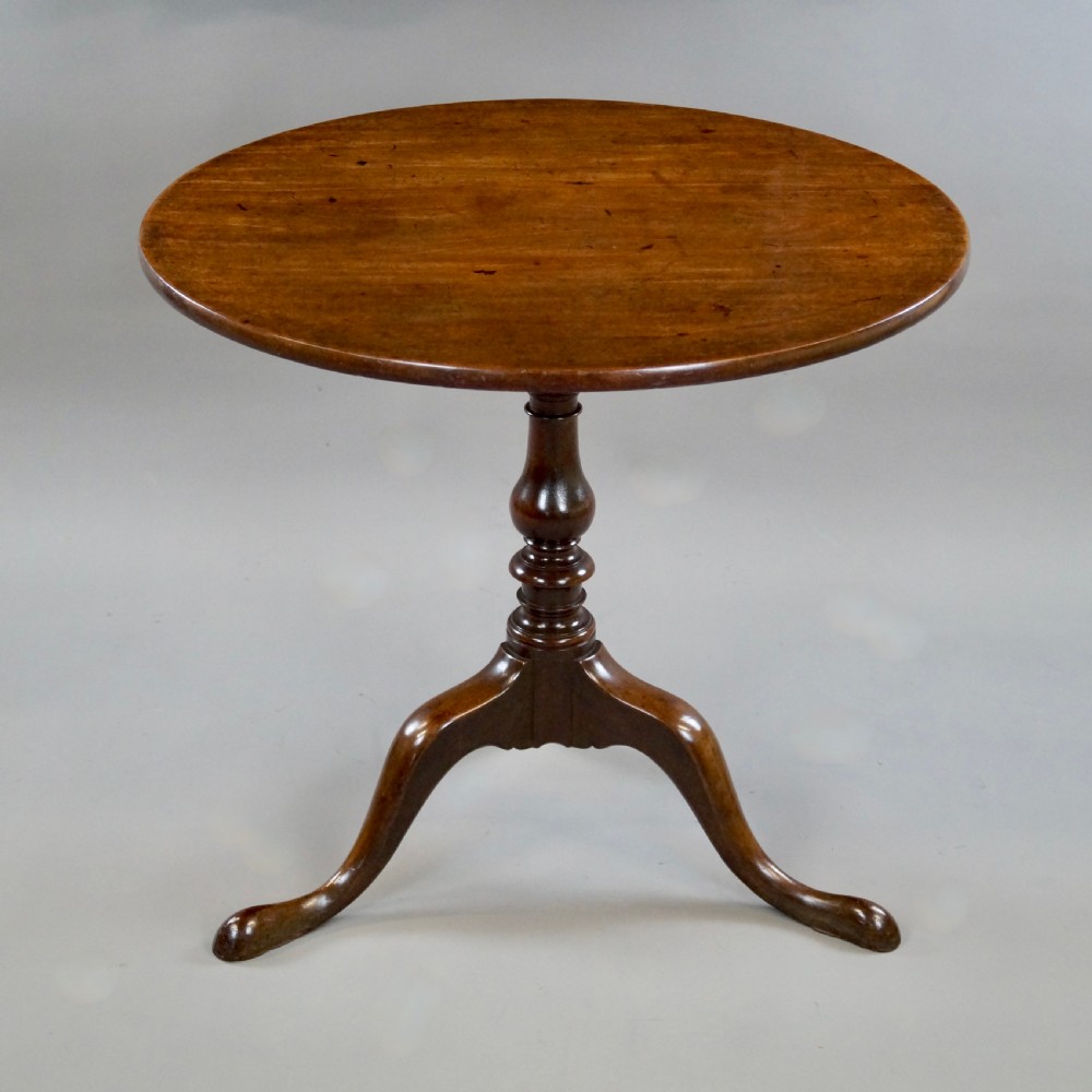 A George III mahogany tripod table featuring a circular tilt top supported by a turned central stem and three cabriole legs. View II
