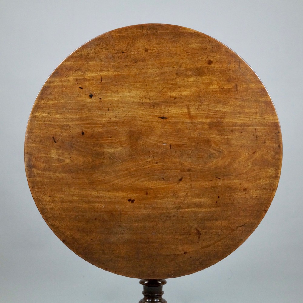 A George III mahogany tripod table featuring a circular tilt top supported by a turned central stem and three cabriole legs. View V