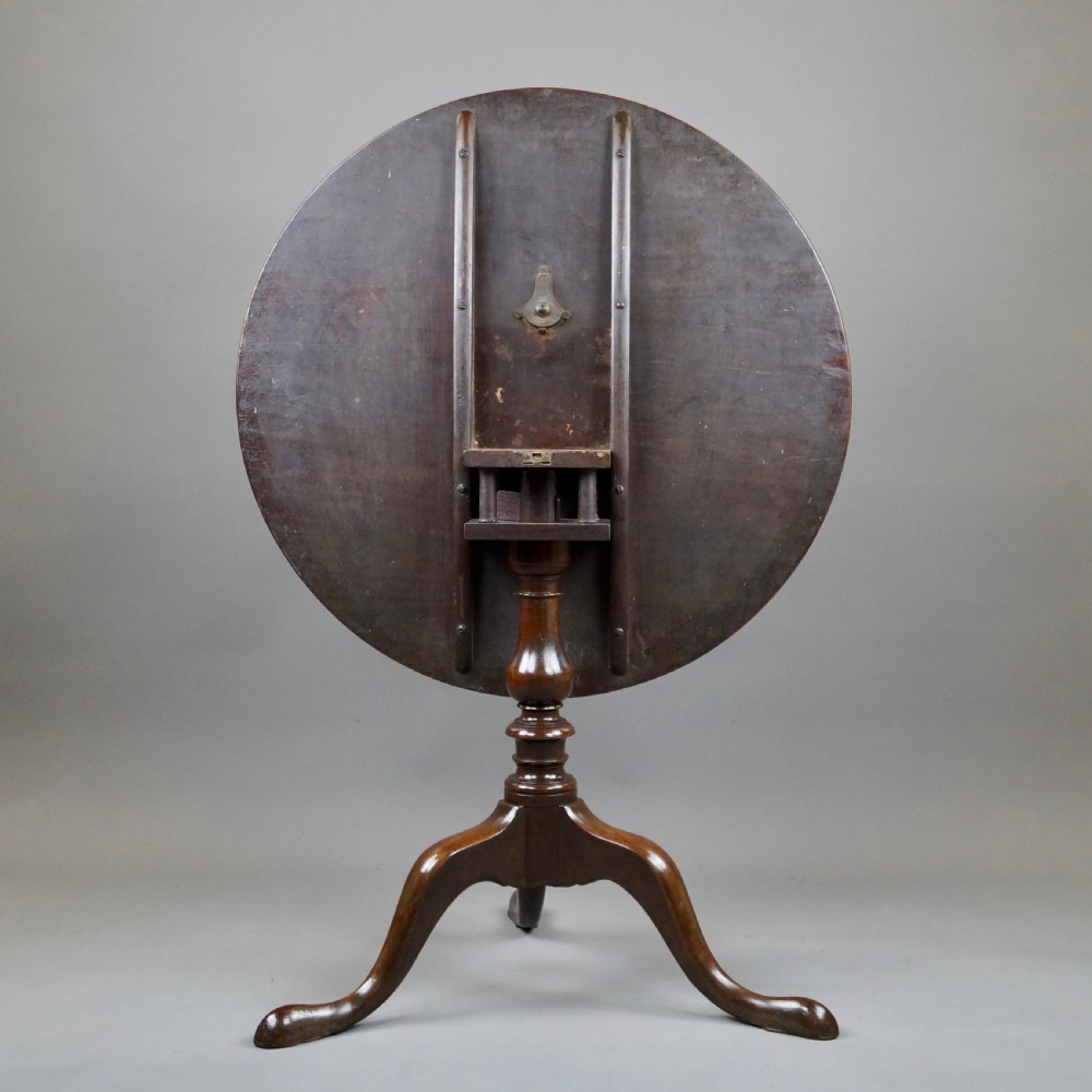 A George III mahogany tripod table featuring a circular tilt top supported by a turned central stem and three cabriole legs. View VI