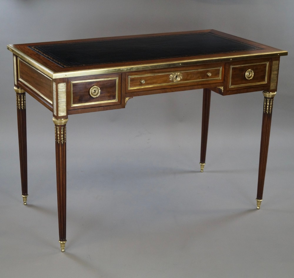 A mahogany writing desk featuring three frieze drawers with brass mounts, a leather-inlaid top, and four tapered fluted legs tipped with brass feet. View III