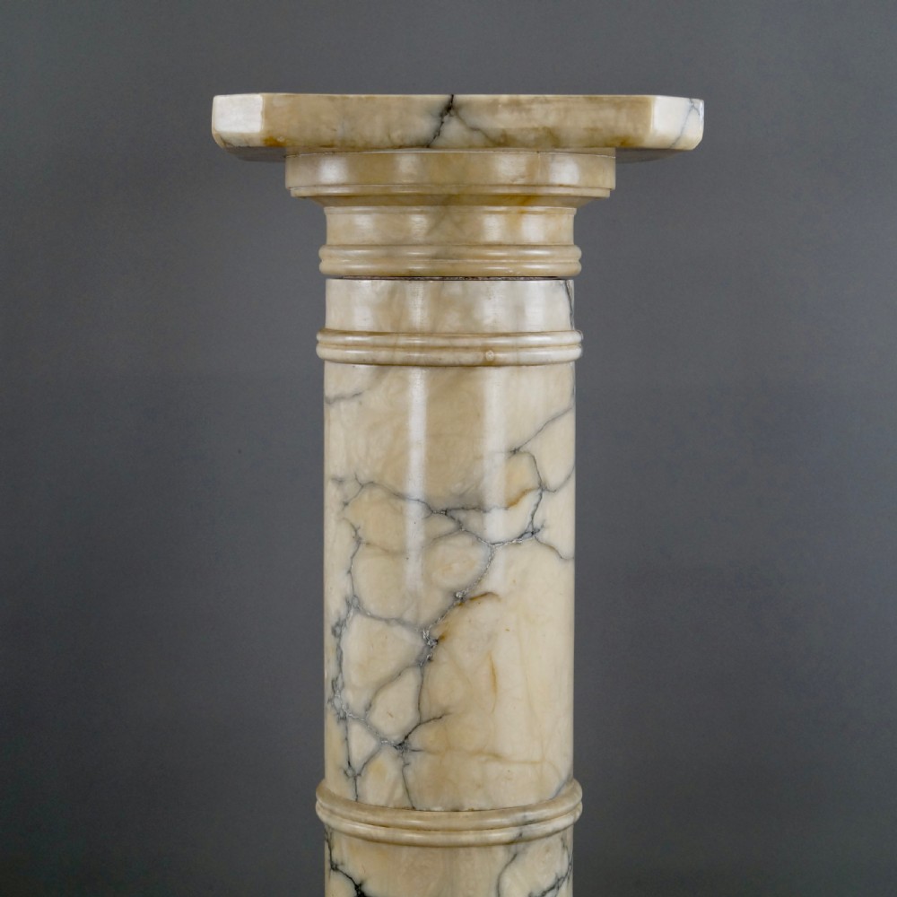 A Neoclassical Arabescato marble column featuring grey veining, a moulded square capital, a cylindrical shaft, and an octagonal base. View II