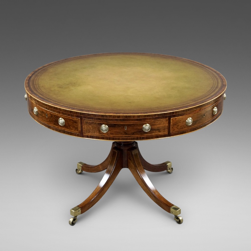 Regency rosewood circular drum table featuring an olive green leather inset top, brass lion-mask drawer handles, and a central pedestal support on splayed quadruped legs with brass castors. View II