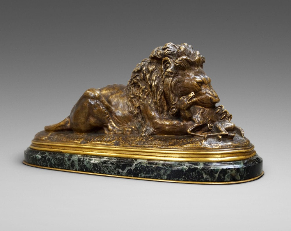 A nineteenth-century French gilded bronze sculpture of a recumbent lion with prey, set upon a moulded green marble plinth.