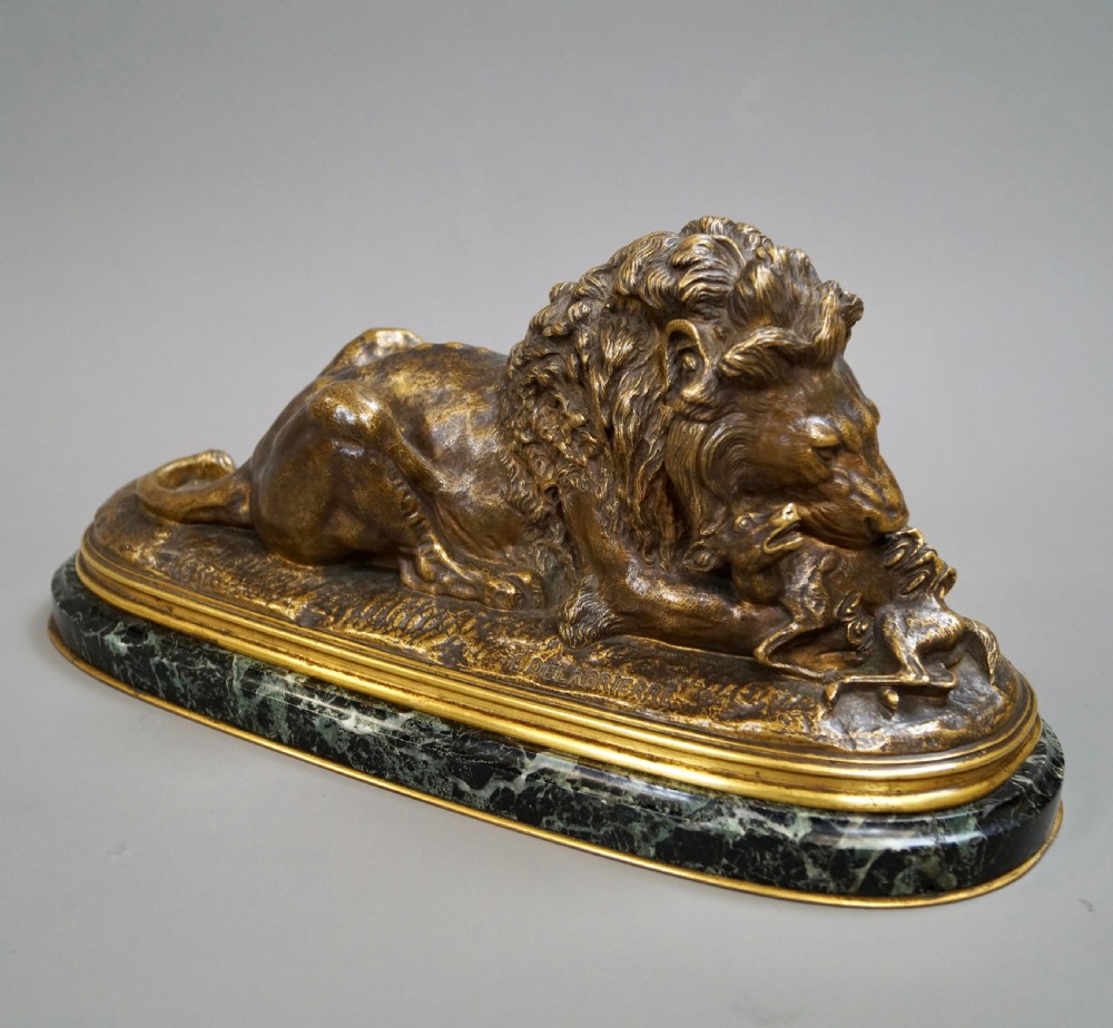 A nineteenth-century French gilded bronze sculpture of a recumbent lion with prey, set upon a moulded green marble plinth. View II