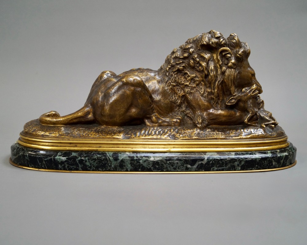 A nineteenth-century French gilded bronze sculpture of a recumbent lion with prey, set upon a moulded green marble plinth. View III