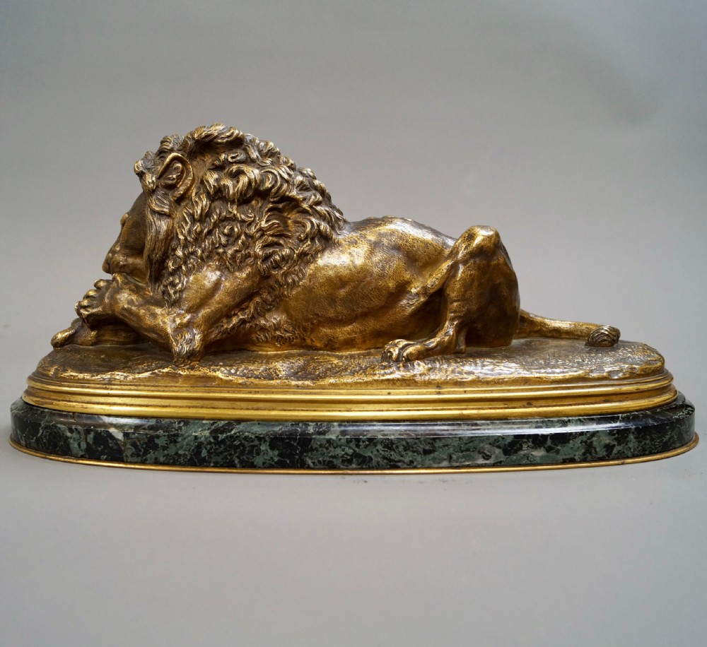 A nineteenth-century French gilded bronze sculpture of a recumbent lion with prey, set upon a moulded green marble plinth. View V