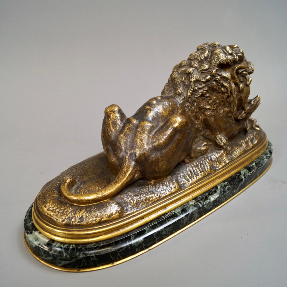 A nineteenth-century French gilded bronze sculpture of a recumbent lion with prey, set upon a moulded green marble plinth. View VI